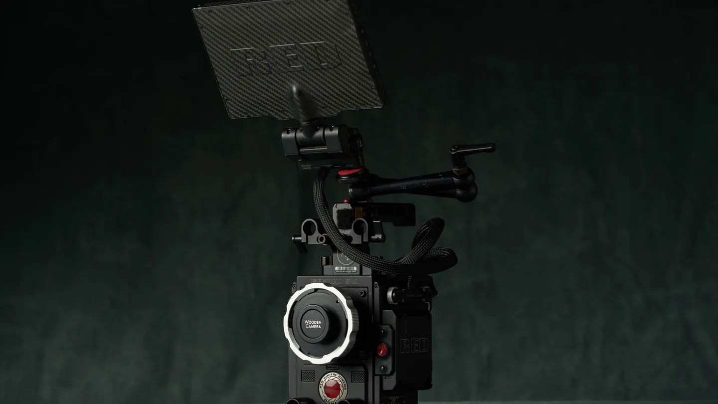 A RED cinema camera body mounted on a Tilta slider, lit low against the studio backdrop.