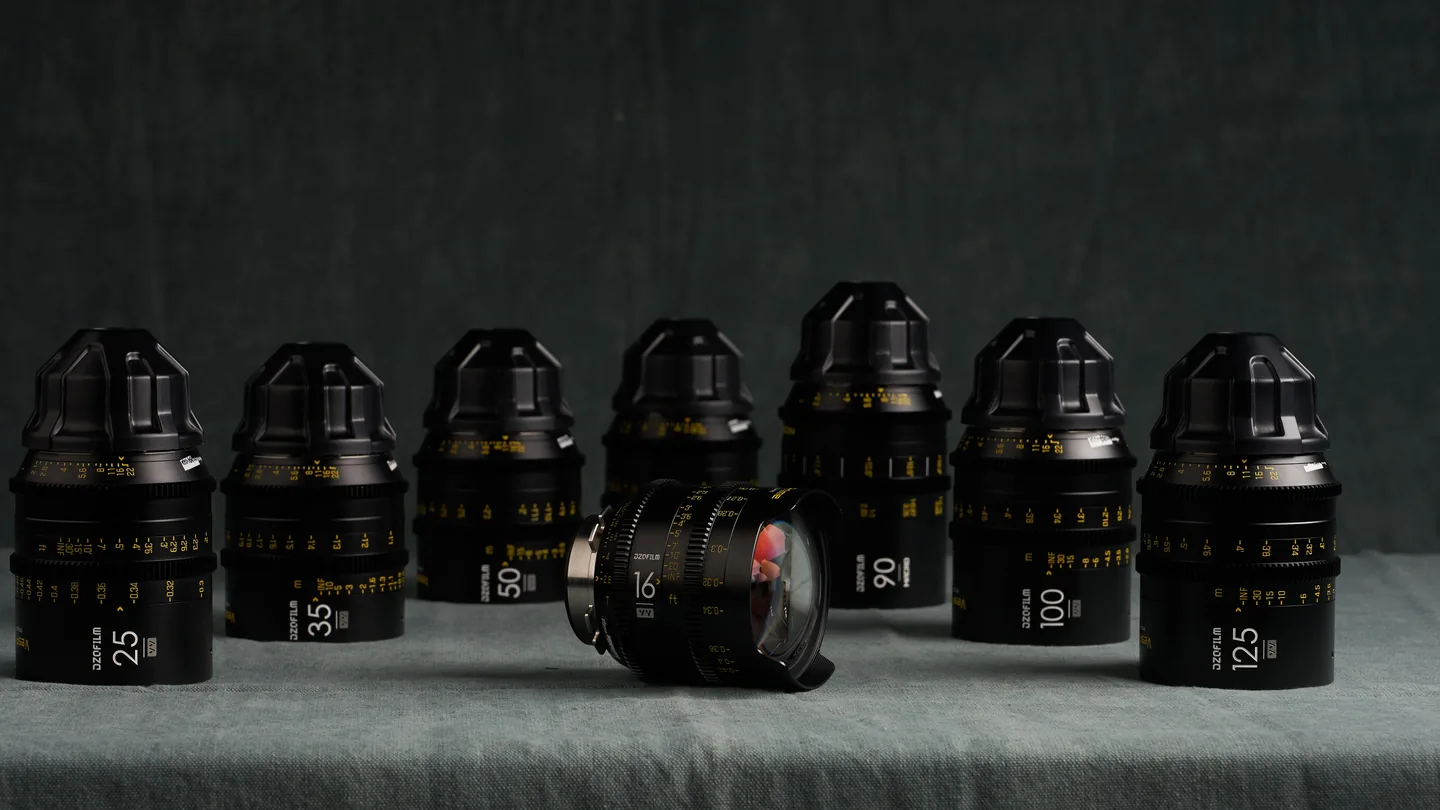 A row of DZO Vespid prime lenses lit low against the studio backdrop.