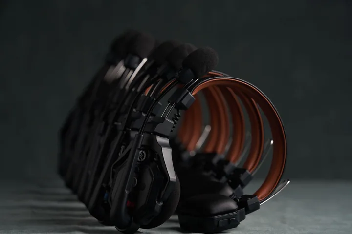 Hollyland C1 Pro comms headsets stacked in a fan against the studio backdrop.