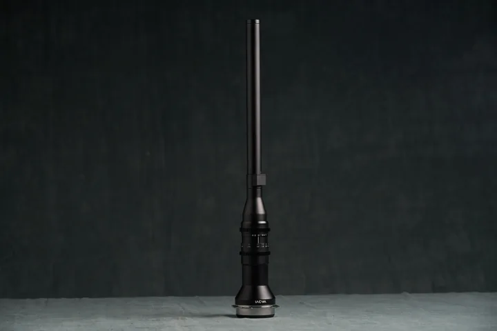 Laowa 24mm probe lens, a long slender barrel, against the studio backdrop.