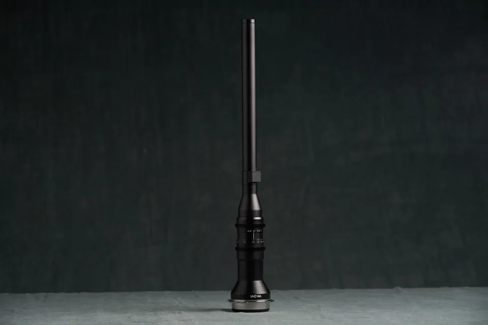 Laowa 24mm probe lens, a long slender barrel, against the studio backdrop.