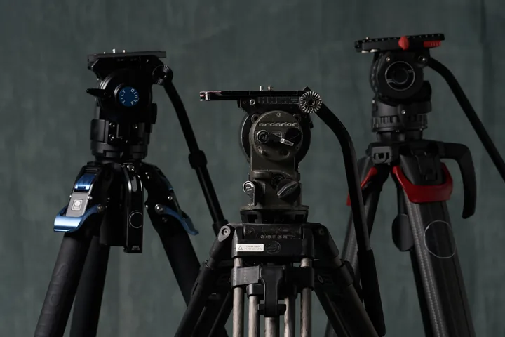 Three lightweight tripods with fluid heads standing against the studio backdrop.