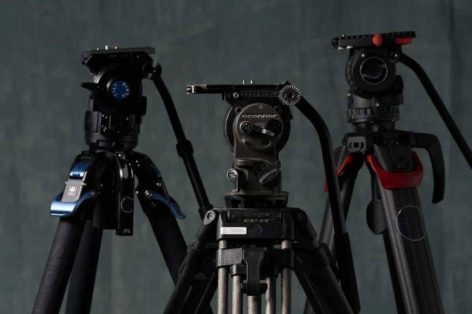 Three lightweight tripods with fluid heads standing against the studio backdrop.